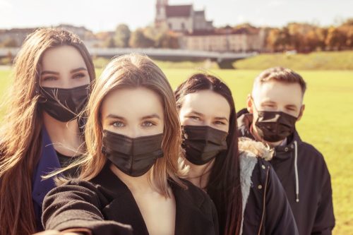 Un groupe de jeunes amis portant des masques faciaux à l'extérieur